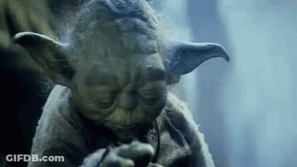 A Close Up Of A Statue Of Yoda From Star Wars Smoking A Pipe . GIF