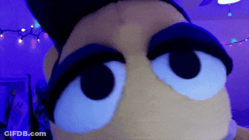 A Close Up Of A Stuffed Animal 'S Eyes In A Purple Room GIF
