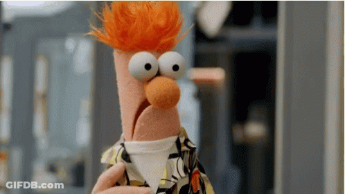 A Close Up Of A Stuffed Animal With Big Eyes And Red Hair Holding A Cup . GIF