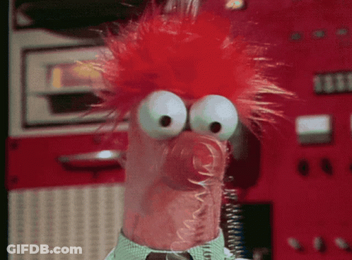 A Close Up Of A Stuffed Animal With Red Hair And Big Eyes GIF