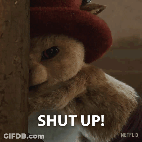 A Close Up Of A Stuffed Animal With The Words Shut Up Written In White GIF