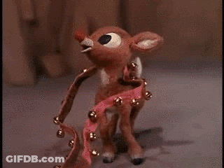 A Close Up Of A Stuffed Reindeer With A Red Nose And A Bell Around Its Neck . GIF