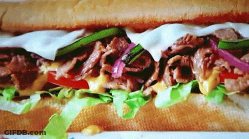 A Close Up Of A Sub Sandwich With Lettuce Tomato And Cheese GIF