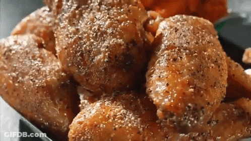 A Close Up Of A Tray Of Chicken Wings With Pepper On Them GIF
