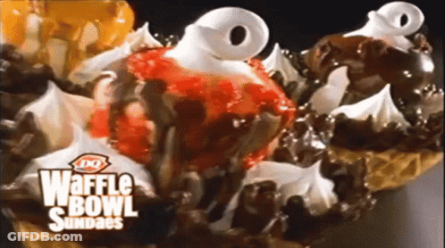 A Close Up Of A Waffle Bowl Sundae With Strawberries Chocolate And Whipped Cream GIF