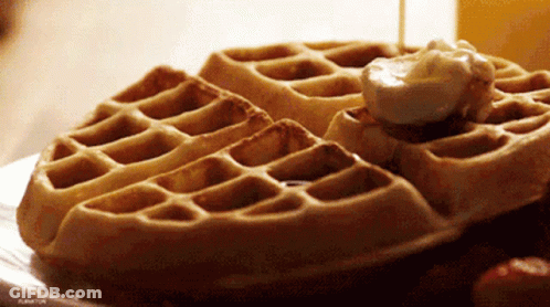 A Close Up Of A Waffle With Syrup And Whipped Cream On It GIF