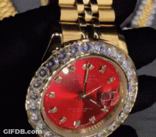A Close Up Of A Watch With A Red Face And Diamonds GIF