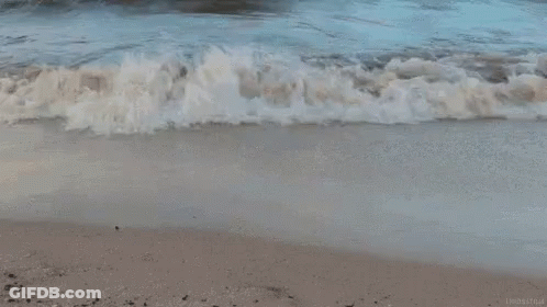 A Close Up Of A Wave Breaking On A Beach . GIF