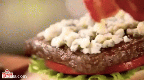 A Close Up Of A Wendy 'S Burger With Lettuce Tomatoes And Blue Cheese GIF