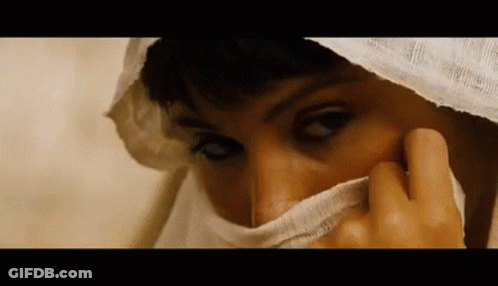 A Close Up Of A Woman Covering Her Face With A White Scarf . GIF