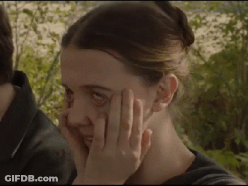 A Close Up Of A Woman Covering Her Face With Her Hand . GIF