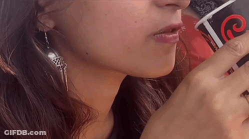 A Close Up Of A Woman Drinking From A Cup That Says Coca Cola On It GIF