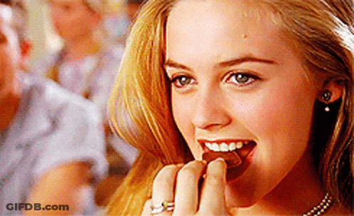 A Close Up Of A Woman Eating A Piece Of Chocolate GIF