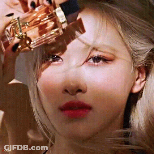 A Close Up Of A Woman Holding A Bottle Of Perfume On Her Forehead . GIF