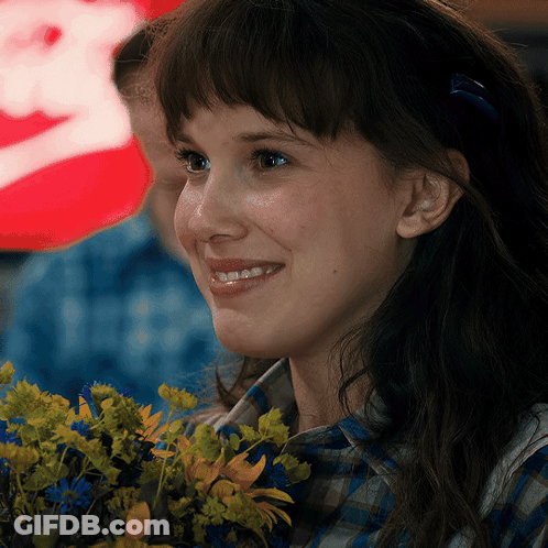 A Close Up Of A Woman Holding A Bouquet Of Flowers And Smiling GIF