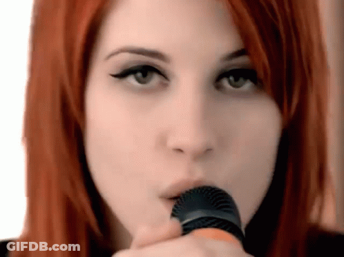 A Close Up Of A Woman Holding A Microphone In Her Mouth . GIF