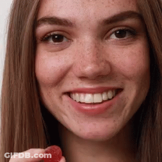 A Close Up Of A Woman Holding A Red Gummy GIF