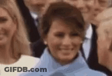 A Close Up Of A Woman In A Blue Coat Smiling In A Crowd Of People . GIF