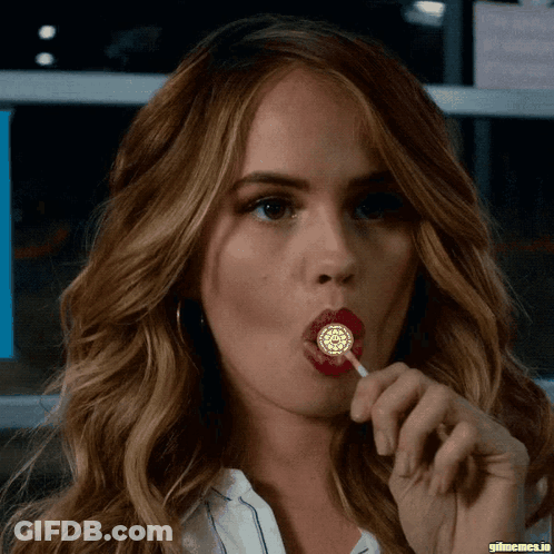 A Close Up Of A Woman Licking A Lollipop With Gifmemes.io In The Corner GIF