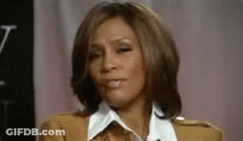 A Close Up Of A Woman Making A Funny Face While Sitting In Front Of A Pink Curtain . GIF