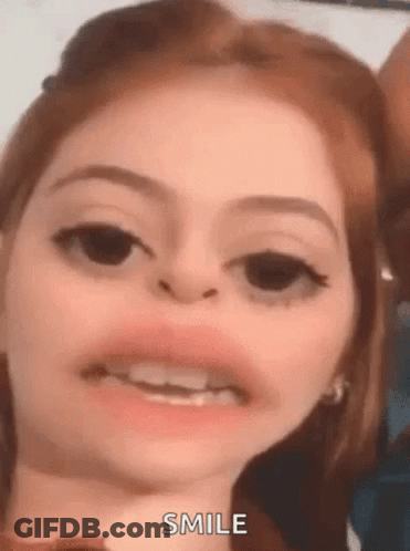 A Close Up Of A Woman Making A Funny Face With Her Mouth Open And Smiling . GIF