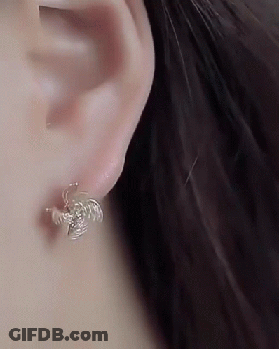 A Close Up Of A Woman 'S Ear Wearing A Pair Of Earrings . GIF