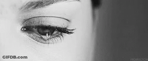 A Close Up Of A Woman 'S Eye With A Tear Running Down It . GIF