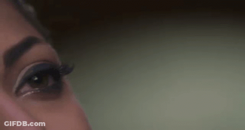 A Close Up Of A Woman 'S Eye With Long Eyelashes And A Green Background . GIF