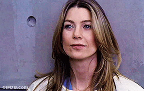 A Close Up Of A Woman 'S Face Against A Gray Wall . GIF