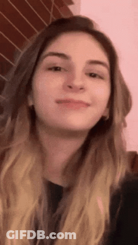 A Close Up Of A Woman 'S Face Against A Pink Background GIF