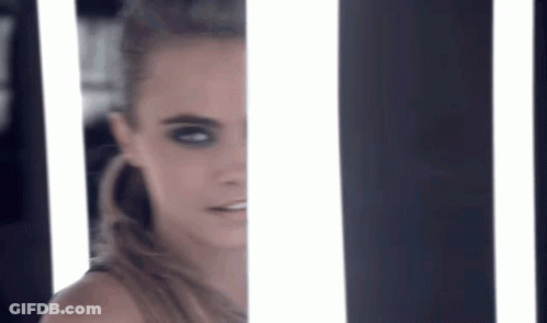 A Close Up Of A Woman 'S Face Behind A Striped Wall With Lights . GIF