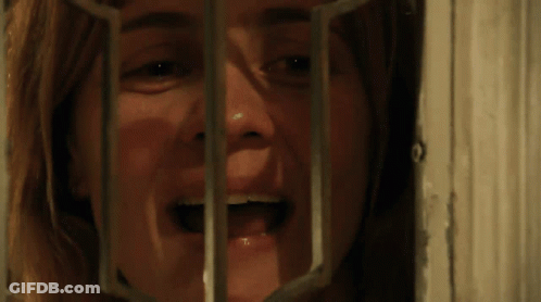A Close Up Of A Woman 'S Face Behind Bars GIF