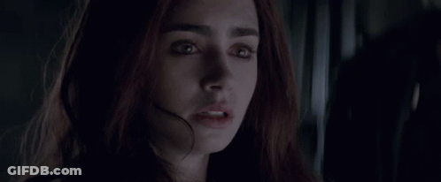 A Close Up Of A Woman 'S Face In A Dark Room Looking At The Camera . GIF