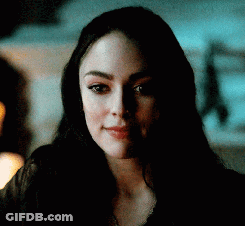 A Close Up Of A Woman 'S Face In A Dark Room Looking At The Camera . GIF