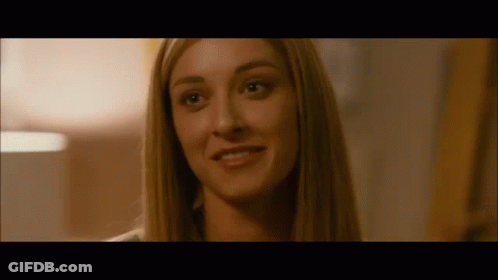 A Close Up Of A Woman 'S Face In A Dark Room Smiling . GIF