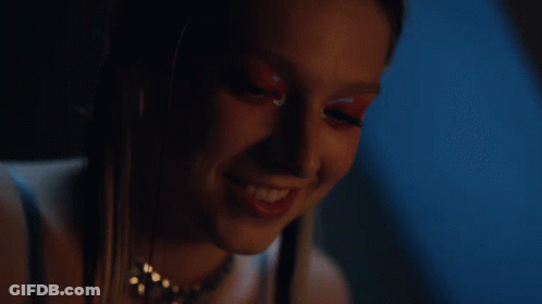 A Close Up Of A Woman 'S Face In A Dark Room With A Blue Background GIF