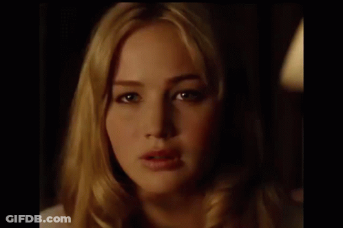 A Close Up Of A Woman 'S Face In A Dark Room With A Light Behind Her . GIF