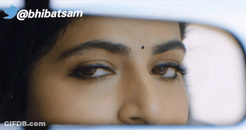 A Close Up Of A Woman 'S Face In A Rear View Mirror With A Twitter Logo In The Background GIF