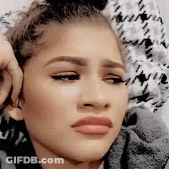 A Close Up Of A Woman 'S Face Making A Funny Face While Sitting On A Bed . GIF