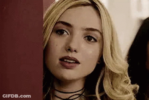 A Close Up Of A Woman 'S Face Peeking Out From Behind A Red Wall . GIF
