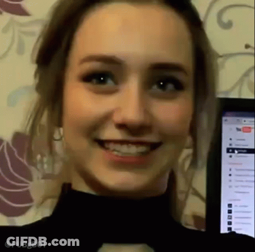 A Close Up Of A Woman 'S Face Smiling In Front Of A Computer Monitor . GIF
