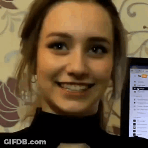 A Close Up Of A Woman 'S Face Smiling In Front Of A Computer Monitor . GIF
