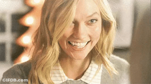 A Close Up Of A Woman 'S Face Smiling With A Christmas Tree In The Background . GIF