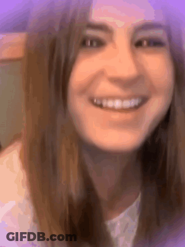 A Close Up Of A Woman 'S Face Smiling With A Purple Background . GIF