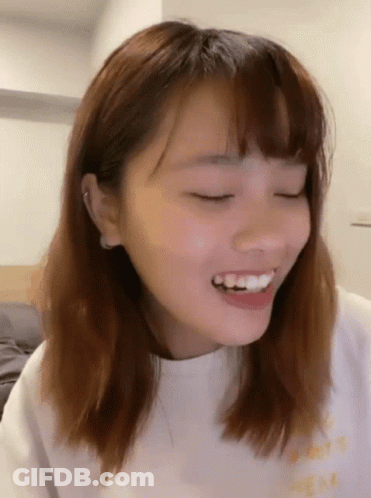 A Close Up Of A Woman 'S Face Smiling With Her Eyes Closed . GIF