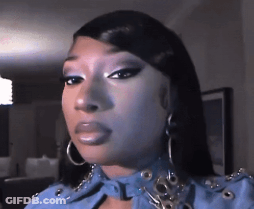 A Close Up Of A Woman 'S Face Wearing A Blue Jacket And Earrings . GIF