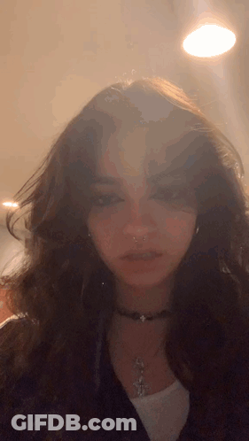 A Close Up Of A Woman 'S Face Wearing A Choker Necklace And Earrings GIF