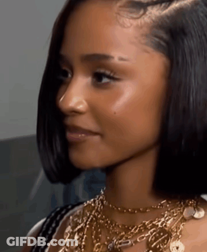 A Close Up Of A Woman 'S Face Wearing A Gold Chain Necklace GIF
