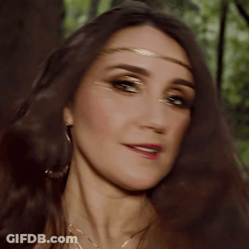 A Close Up Of A Woman 'S Face Wearing A Gold Headband GIF