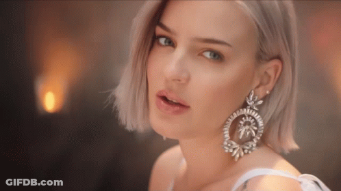 A Close Up Of A Woman 'S Face Wearing A Pair Of Earrings GIF